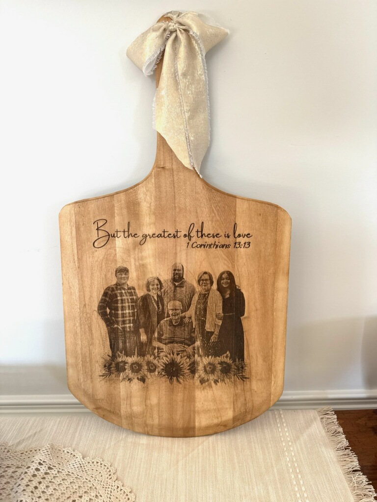 Engraved wooden serving board with a family portrait, sunflowers and the verse “But the greatest of these is love — 1 Corinthians 13:13”